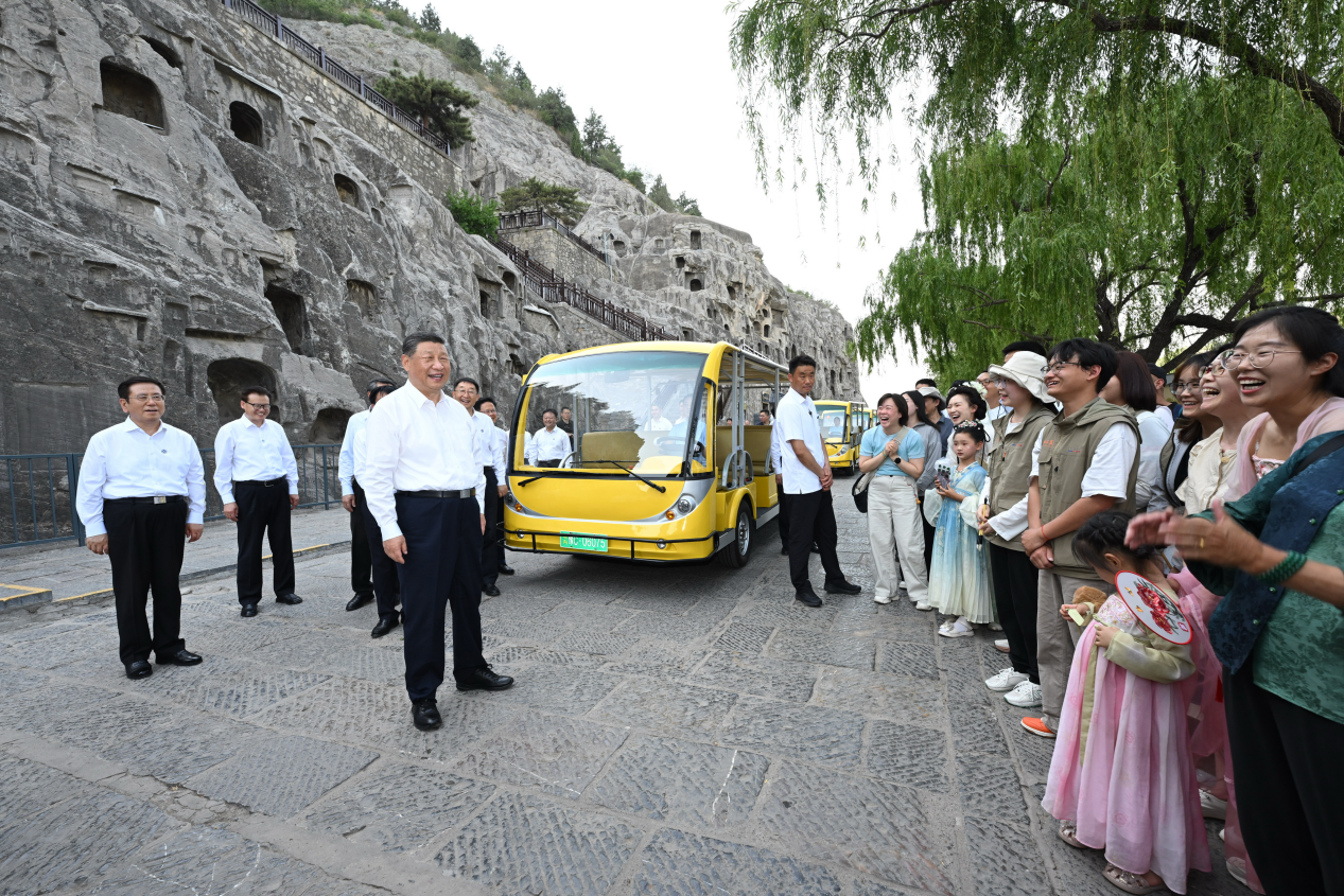 5月19日,习近平在洛阳龙门石窟考察时,同游客亲切交流。